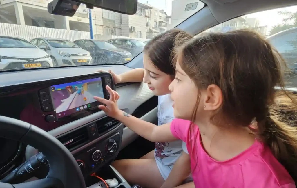 ילדות משחקות במשחק מחשב במסך בתוך הרכב